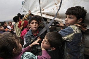 毛布と枕の配給に群がる難民キャンプの子供たち