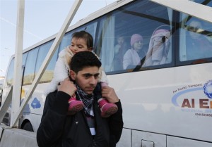 幼い妹を方に乗せ、ロシア人を乗せたバスの脇を行き過ぎるシリア人の男性。彼等もダマスカスから逃れてきた避難民である。